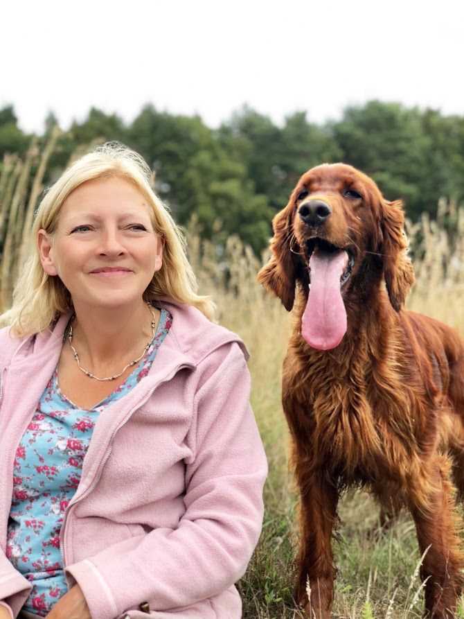 Rosemary Charlish sitting in a meadow with one of her Irish Setters